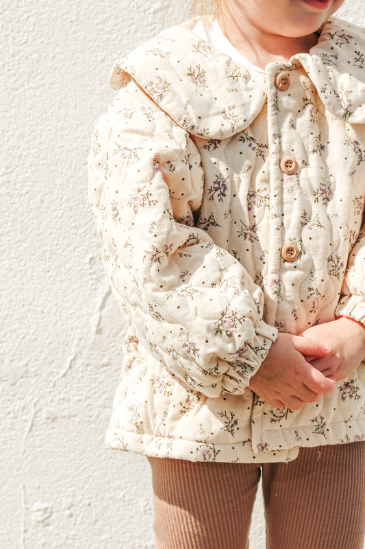 Child wearing a floral-patterned coat against a light background